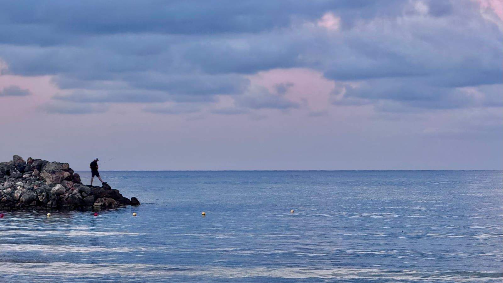 Abendstimmung an der Küste von Rethymnon auf Kreta: ruhiges Meer und Felsmole in der Dämmerung