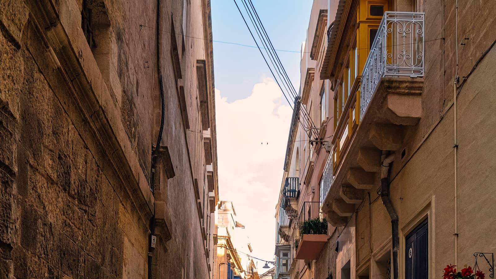 Typische Altstadtgasse auf Malta mit Kalksteinfassaden und bunten Balkonen